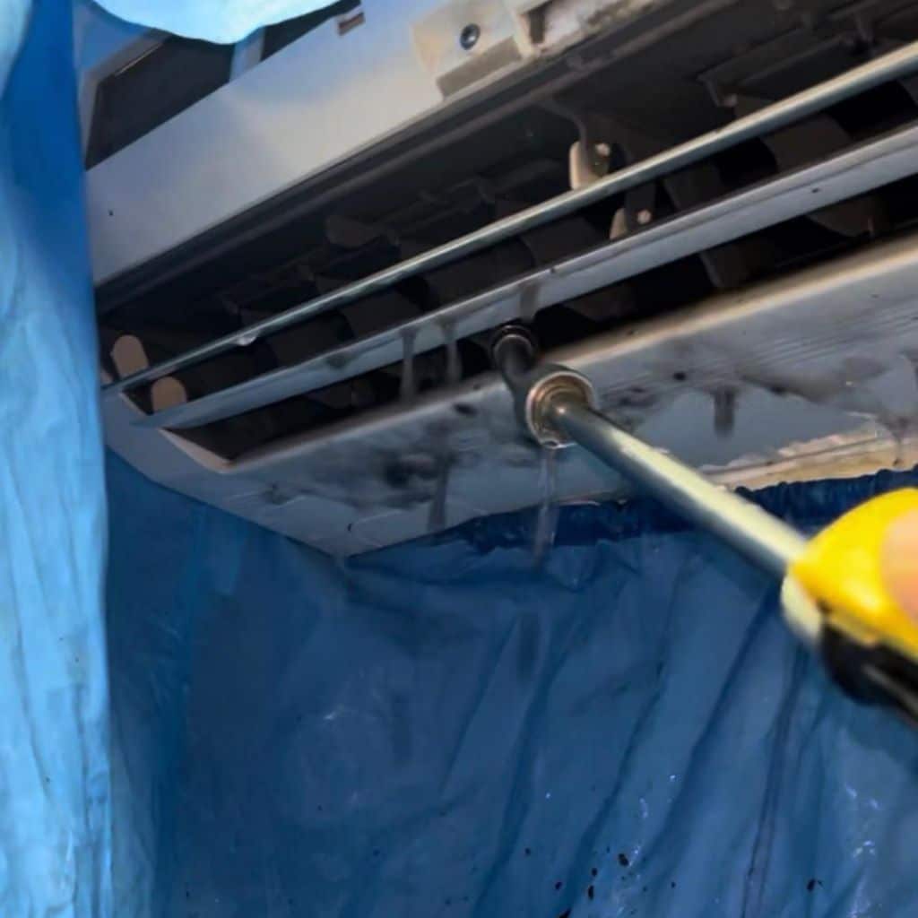 Technicien Efficience réalisant le nettoyage d'une climatisation avec protection